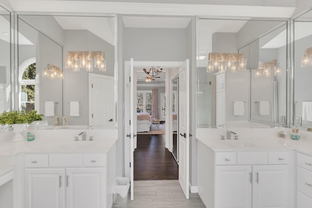 ensuite bathroom with ensuite bathroom, wood finished floors, two vanities, and a sink