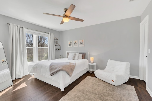 bedroom with dark wood-type flooring, a ceiling fan, and baseboards