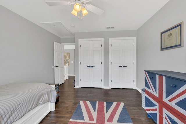 bedroom featuring attic access, visible vents, two closets, and wood finished floors