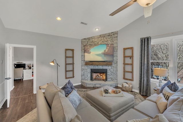 living room with lofted ceiling, recessed lighting, visible vents, a stone fireplace, and wood finished floors