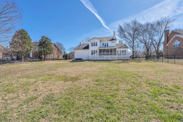 rear view of house with a sunroom, fence, and a lawn