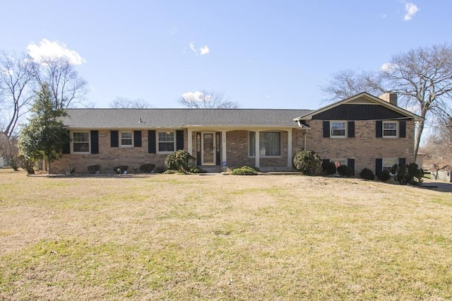 view of front of home with a front yard, a chimney, and brick siding