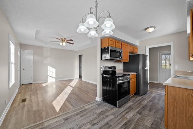 kitchen with stainless steel appliances, a raised ceiling, light countertops, visible vents, and light wood-type flooring