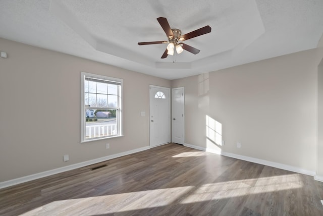 foyer entrance featuring a raised ceiling, visible vents, baseboards, and wood finished floors