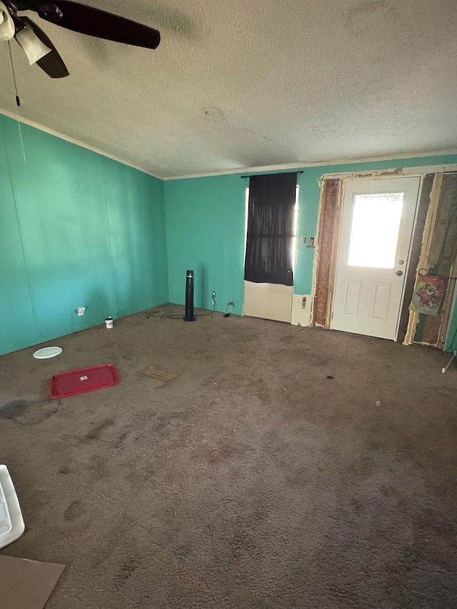 empty room with ceiling fan, a textured ceiling, and carpet flooring