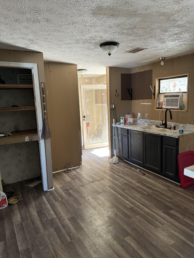 interior space featuring a textured ceiling, cooling unit, wood finished floors, a sink, and visible vents