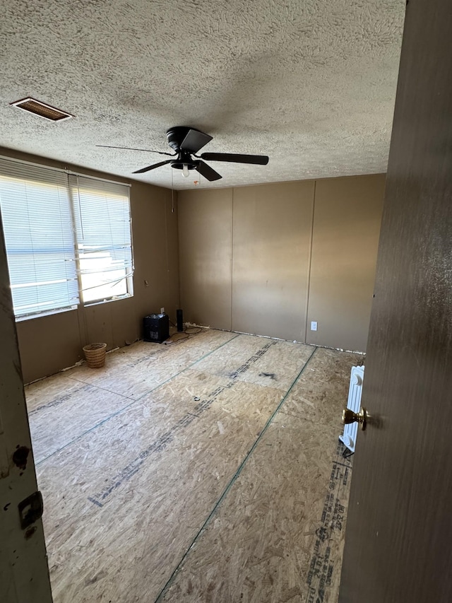 unfurnished room featuring a ceiling fan, visible vents, and a textured ceiling