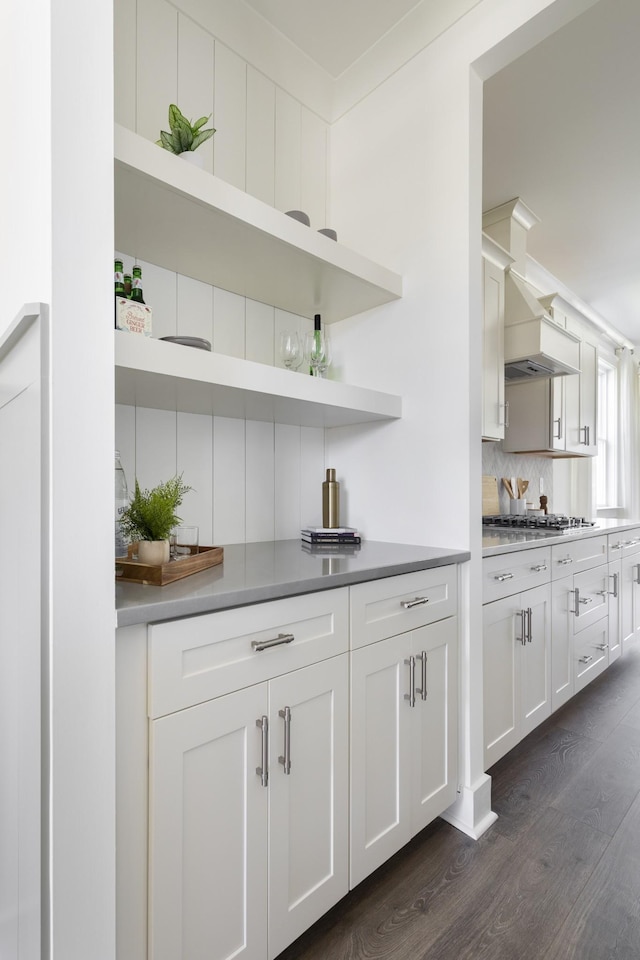 bar with stainless steel gas cooktop, dark wood-type flooring, ornamental molding, and decorative backsplash