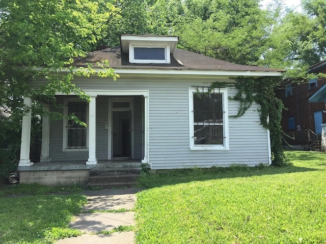 bungalow with covered porch and a front lawn