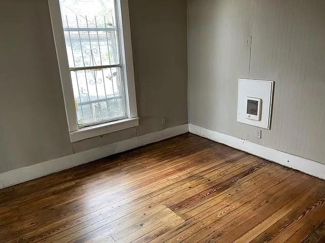 spare room featuring dark wood-style floors, plenty of natural light, and baseboards