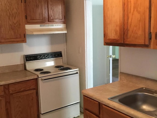 kitchen featuring electric stove, brown cabinetry, light countertops, and under cabinet range hood