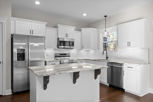 kitchen with appliances with stainless steel finishes, a breakfast bar, white cabinetry, and a sink