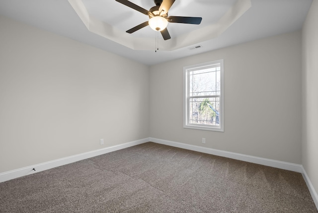 carpeted spare room featuring ceiling fan, baseboards, visible vents, and a raised ceiling