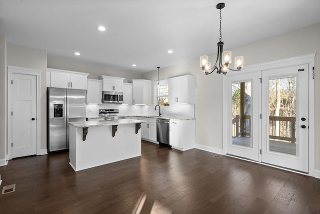 kitchen with dark wood finished floors, tasteful backsplash, appliances with stainless steel finishes, a sink, and a kitchen breakfast bar