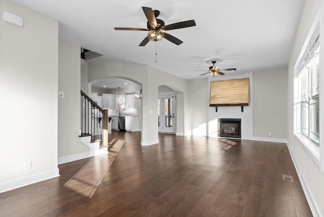 unfurnished living room with a fireplace, stairway, baseboards, and wood finished floors