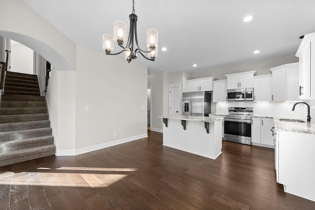 kitchen featuring dark wood-style flooring, a breakfast bar area, stainless steel appliances, white cabinetry, and a sink