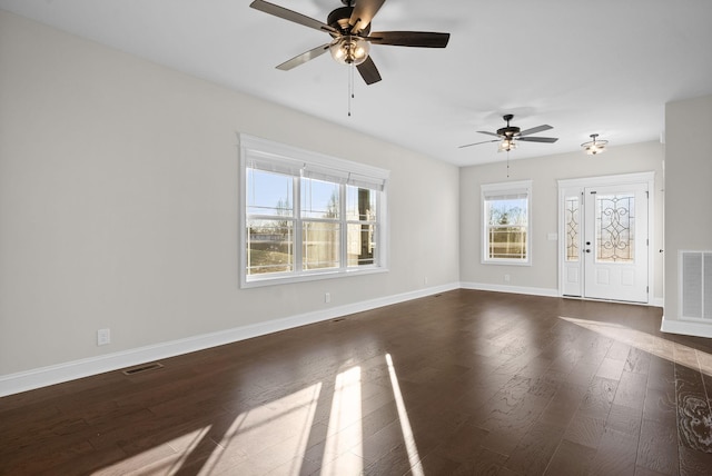 spare room featuring a ceiling fan, visible vents, dark wood finished floors, and baseboards