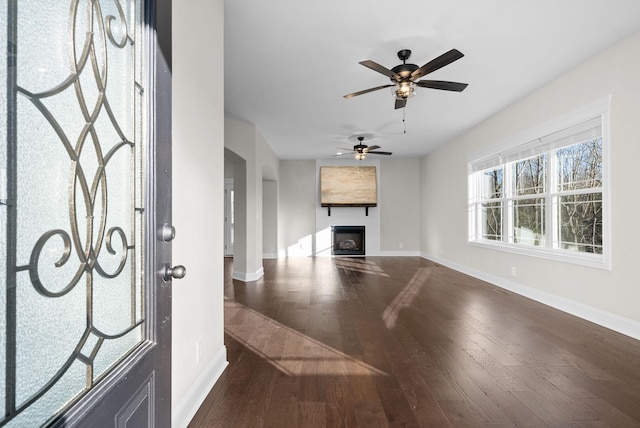 foyer entrance featuring a fireplace, baseboards, and dark wood-type flooring