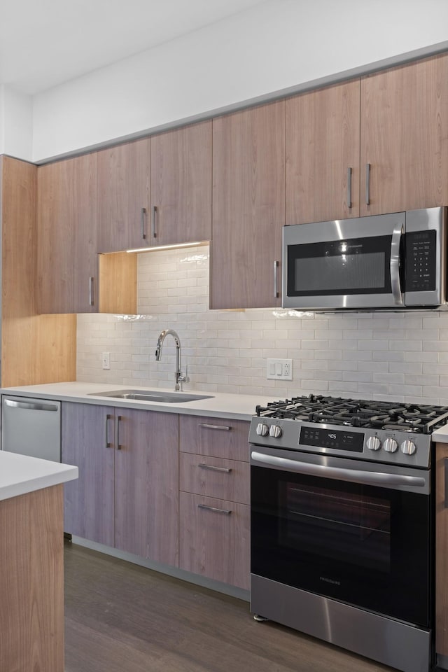 kitchen featuring a sink, dark wood finished floors, light countertops, stainless steel appliances, and modern cabinets