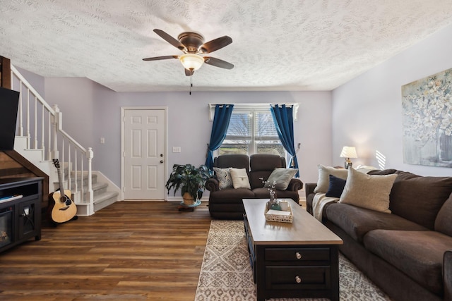 living room with dark wood-style floors, stairs, a ceiling fan, and a textured ceiling