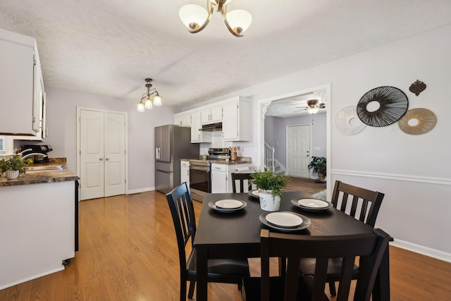 dining room featuring a textured ceiling, stairway, wood finished floors, and baseboards