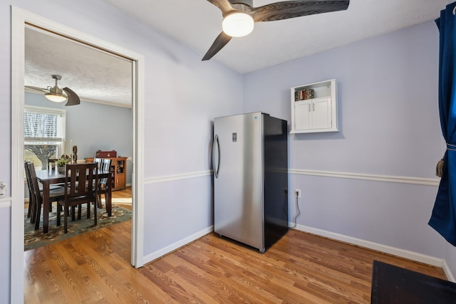 kitchen with light wood-style flooring, baseboards, a ceiling fan, and freestanding refrigerator