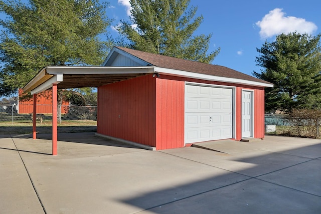 garage with a garage, driveway, and fence