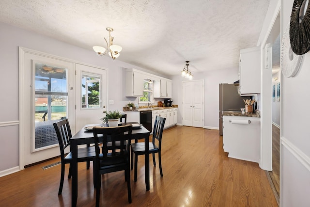 dining area with baseboards, visible vents, wood finished floors, an inviting chandelier, and a textured ceiling