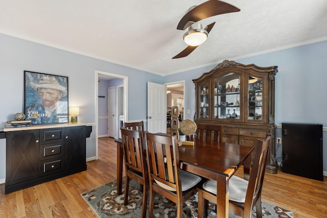 dining area with light wood-type flooring, ceiling fan, baseboards, and crown molding