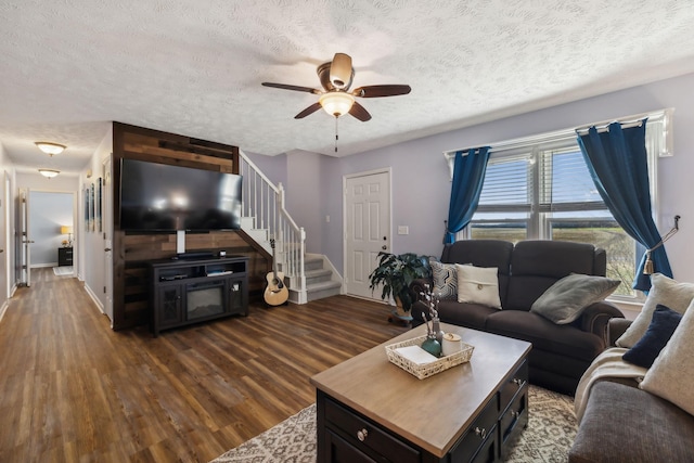 living room featuring stairs, ceiling fan, a textured ceiling, and dark wood-style floors