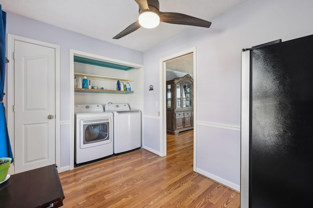 laundry area with light wood-style flooring, laundry area, a ceiling fan, baseboards, and independent washer and dryer