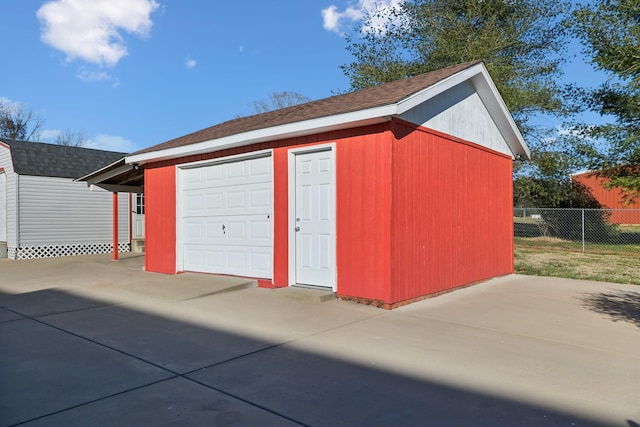 garage with concrete driveway and fence