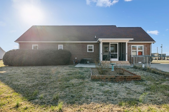 back of property with brick siding, fence, a sunroom, a lawn, and a patio area