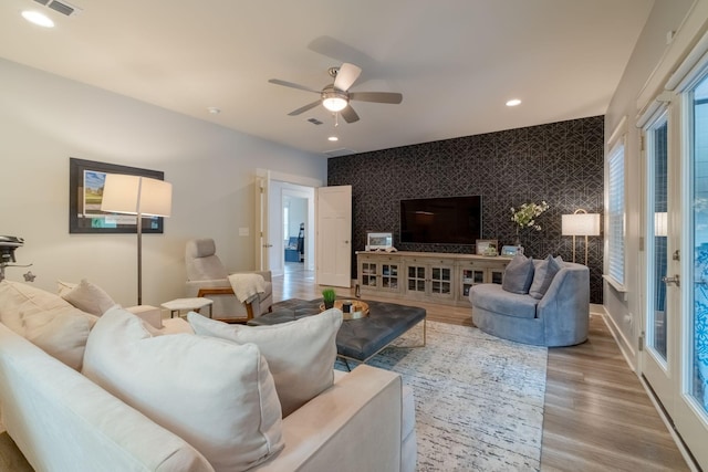 living area with wallpapered walls, baseboards, an accent wall, wood finished floors, and recessed lighting