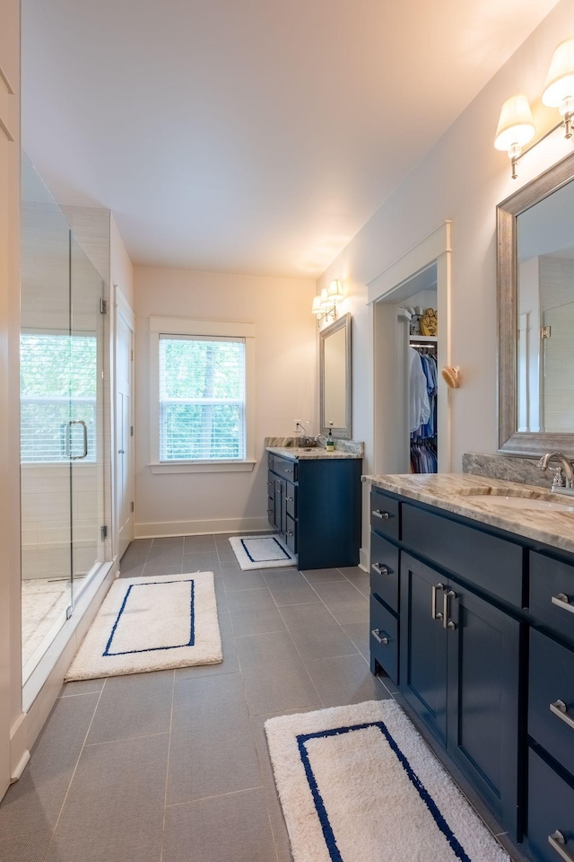 bathroom featuring tile patterned flooring, two vanities, a sink, and a shower stall