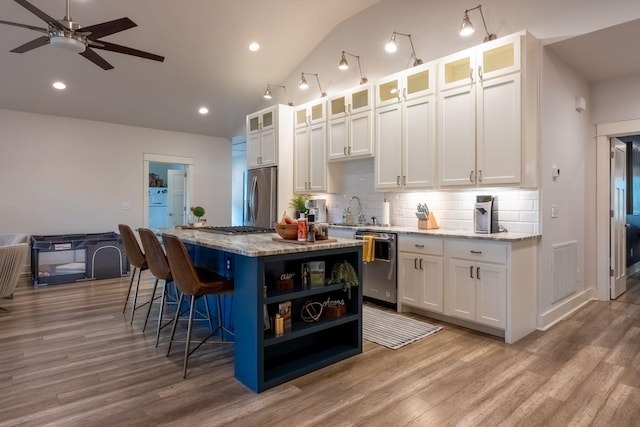 kitchen with appliances with stainless steel finishes, white cabinets, visible vents, and a kitchen island