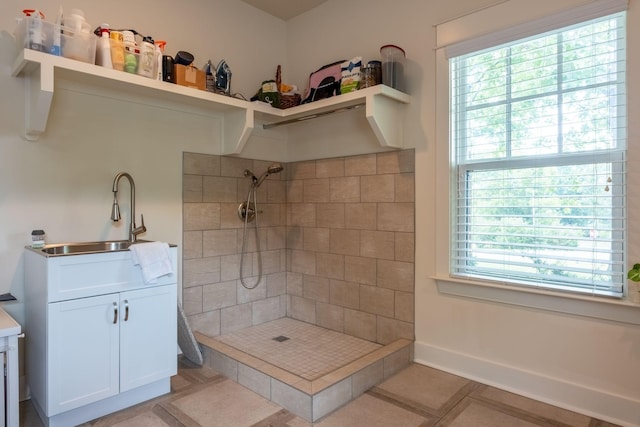 bathroom featuring baseboards, tiled shower, vanity, and tile patterned floors