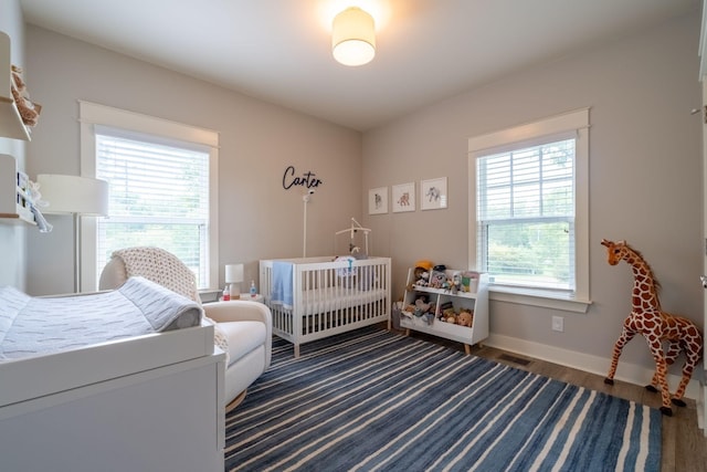 bedroom featuring multiple windows, visible vents, baseboards, and wood finished floors