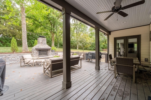 wooden deck with french doors, ceiling fan, grilling area, and an outdoor living space with a fireplace