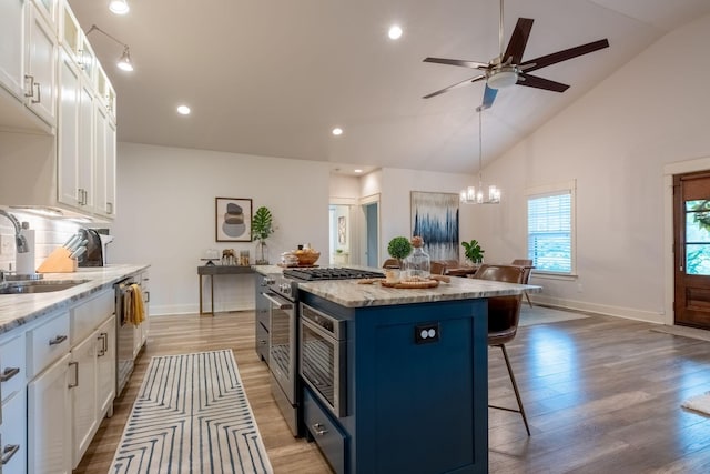 kitchen featuring blue cabinets, stainless steel appliances, a breakfast bar, a sink, and white cabinets