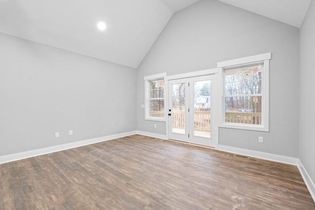 spare room with high vaulted ceiling, visible vents, baseboards, and wood finished floors