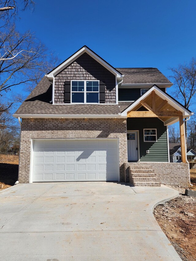 view of front of property with an attached garage, a shingled roof, concrete driveway, and brick siding