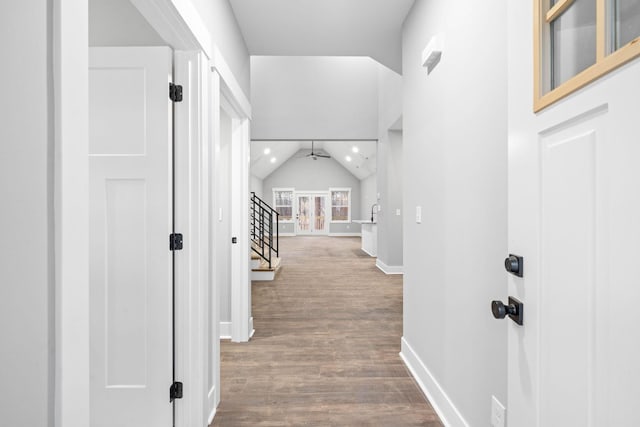 corridor featuring dark wood-style floors, recessed lighting, stairway, vaulted ceiling, and baseboards