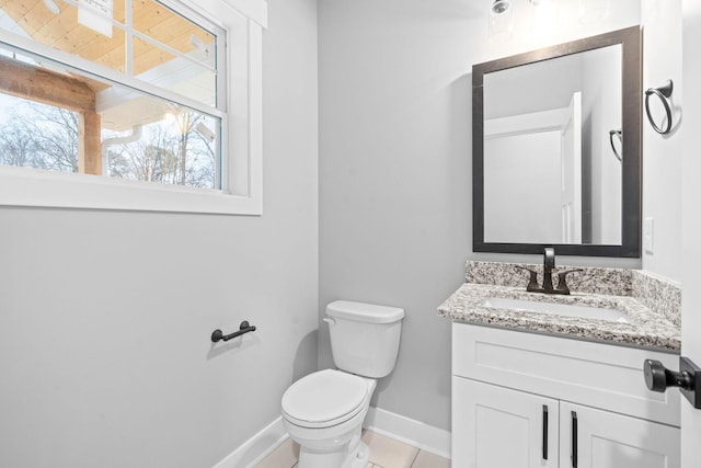 half bathroom featuring toilet, vanity, baseboards, and tile patterned floors