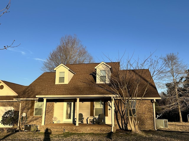 back of house with covered porch, central AC, brick siding, and a shingled roof