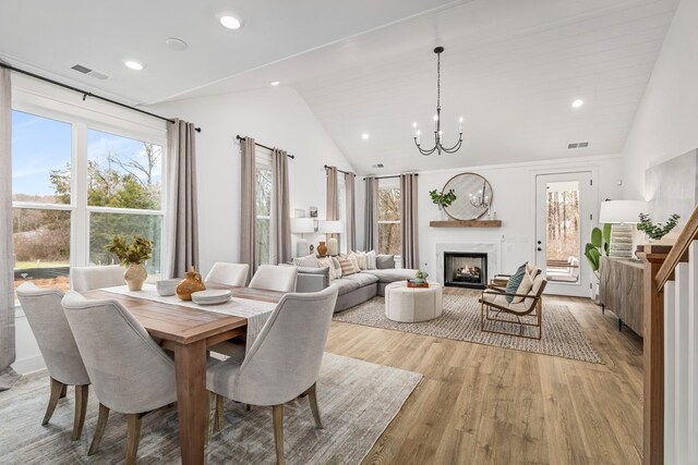 dining room with light wood-type flooring, a premium fireplace, visible vents, and a notable chandelier