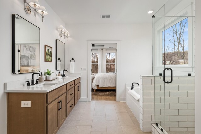 ensuite bathroom featuring double vanity, visible vents, tile patterned floors, a sink, and a bath