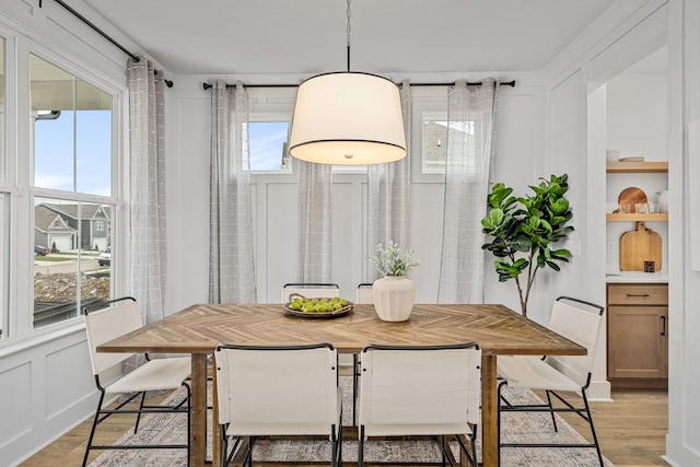 dining space featuring light wood-type flooring and a decorative wall