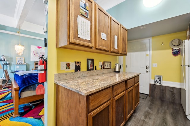 kitchen featuring dark wood-style floors, freestanding refrigerator, brown cabinetry, and light stone countertops