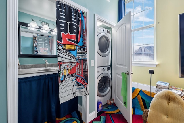 laundry room featuring a sink, baseboards, and stacked washer / dryer